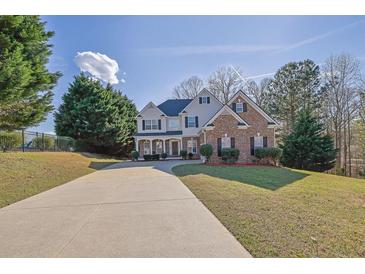 Charming two-story home features a brick and siding facade, well-maintained landscaping, and a long driveway at 917 Redstone Trl, Dacula, GA 30019