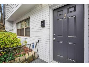 The front door to unit 6 is painted in a dark color, with a brass knocker and brick exterior at 1683 Briarcliff Rd # 6, Atlanta, GA 30306