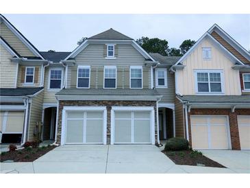 Charming townhome featuring stone accents, a two-car garage, and neutral siding at 1905 Granville Dr, Lawrenceville, GA 30043