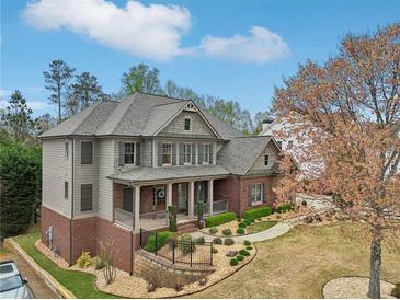 Stunning two-story home showcasing a brick facade, covered porch, manicured landscaping, and a well-maintained lawn at 1870 Marcia Overlook Dr, Cumming, GA 30041