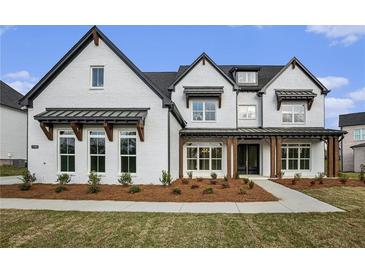 A stylish two-story home with white brick, black trim, covered entry and manicured front yard at 7785 Wild Violet Dr, Cumming, GA 30040
