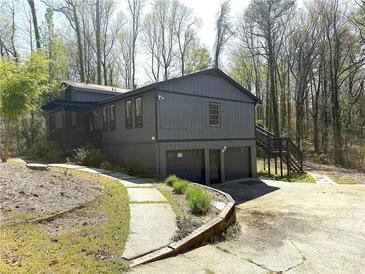 Two-story home with gray siding, a two-car garage, and a landscaped front yard surrounded by mature trees at 2919 Manitoba Ln, Marietta, GA 30062