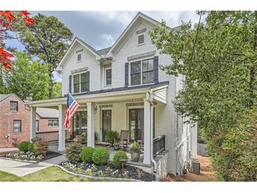 Charming two-story white brick home with a welcoming front porch, landscaped yard and an American flag at 555 E Wesley Ne Rd, Atlanta, GA 30305