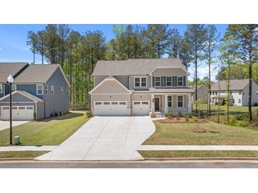 Two-story home with stone accents, three-car garage, long driveway and manicured lawn at 59 Tallulah Trl, Sharpsburg, GA 30277