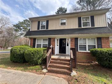 Charming two-story home featuring a brick facade, black shutters and a well-manicured front yard at 1606 King Rd, Riverdale, GA 30296