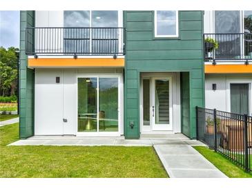 Modern townhome showcasing a vibrant green exterior, clean lines, a small balcony, and a well-maintained lawn at 2029 Memorial Dr # 32, Atlanta, GA 30317