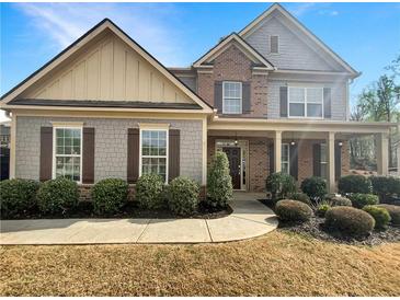 Charming two-story home featuring a mix of brick and stone accents, complemented by lush landscaping and a welcoming entrance at 3305 Pleasant Manor Ct, Cumming, GA 30028
