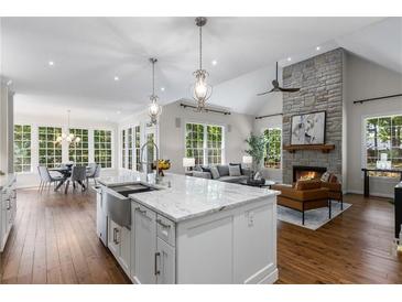 Open-concept living area boasts a stone fireplace, hardwood floors, and large windows with natural light at 3895 Overlake Dr, Cumming, GA 30041