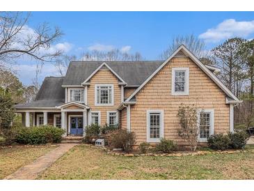 Charming two-story home with wood siding, complemented by lush landscaping and a welcoming blue front door at 905 Attaway Rd, Bowdon, GA 30108