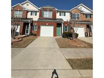 Traditional brick townhome with a two-car garage and manicured lawn at 91 Brookway Trce, Norcross, GA 30071