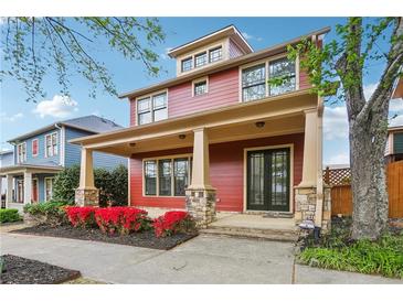 Charming two-story home with a covered porch and stone accents, complemented by red flowering shrubs at 9942 Ashton Old Rd, Douglasville, GA 30135