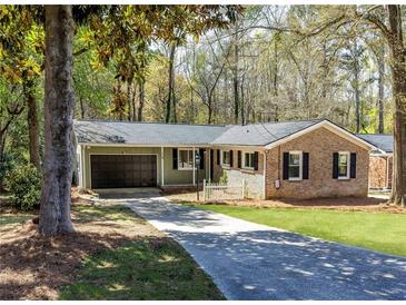 Charming single-story home with brick and siding exterior, lush lawn, and an attached garage in a wooded setting at 1488 Drayton Woods Dr, Tucker, GA 30084