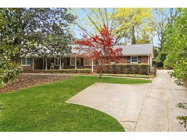 Charming single-story brick home with a well-manicured lawn, mature trees, and a paved driveway at 5630 Lake Forrest Dr, Sandy Springs, GA 30342