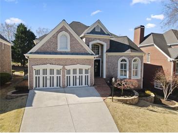 Charming brick home with a two-car garage and well-manicured landscaping, perfect for curb appeal at 5325 Davenport Mnr, Cumming, GA 30041