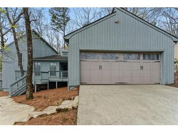 Charming home exterior featuring an attached garage and covered porch entry at 135 S Falcon Blf, Alpharetta, GA 30022
