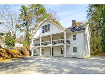 Stately two-story home features a prominent upper-level balcony, white siding, and a spacious front yard with ample parking at 1596 Willowbrook Sw Dr, Atlanta, GA 30311