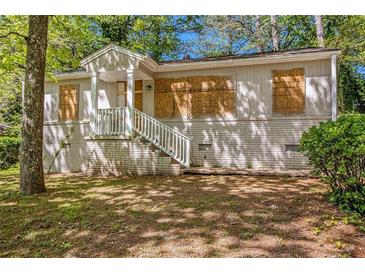 Exterior front of single story home with white brick foundation, stairs and boarded up windows at 1907 Oak Valley Rd, Decatur, GA 30035