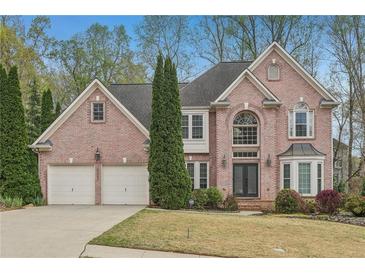 Charming two-story brick home with well-maintained landscaping and a two-car garage on a sunny day at 3887 Hickory Manor Dr, Suwanee, GA 30024
