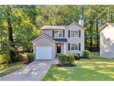 Charming two-story home features a manicured lawn, attached garage and lush landscaping at 5570 Downs Way, Lithonia, GA 30058