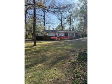 Charming single story brick home with manicured lawn and colorful azalea bushes in front at 3674 Canton Rd, Marietta, GA 30066