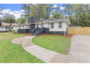 Charming one-story home with manicured front yard, walkway, brick chimney, and a newly installed fence at 1990 Venetian Sw Dr, Atlanta, GA 30311