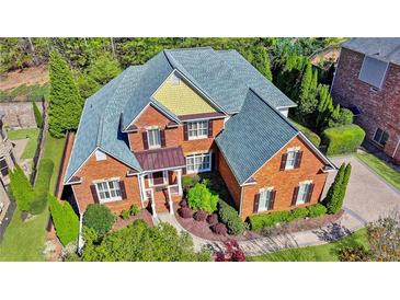 Stunning traditional brick home with mature landscaping, a charming front porch and a beautiful roofline at 7940 Royal Melbourne Way, Duluth, GA 30097