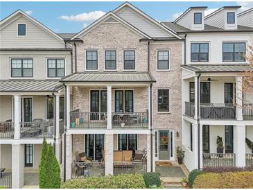 Beautiful townhome featuring brick facade, double balconies, and well-maintained landscaping at 115 Harlow Cir, Roswell, GA 30076
