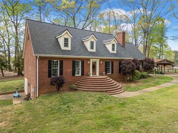 Charming brick home featuring a manicured lawn, mature trees, and a cozy front entrance with decorative shrubbery at 6695 Woodstock Rd, Acworth, GA 30102