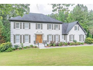 Charming two-story brick home featuring a well-manicured lawn and lush landscaping at 3442 Inns Brook Way, Snellville, GA 30039