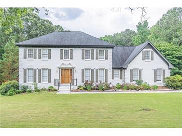 Charming two-story home with white brick exterior, gray shutters, and a lush green lawn at 3442 Inns Brook Way, Snellville, GA 30039
