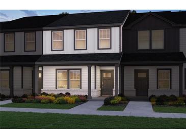 Charming two-story townhome featuring white siding, black trim, covered entryway and colorful landscaping at 2270 Ashton Dr, Conyers, GA 30013