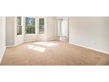 Bright, carpeted living room featuring a bay window letting in ample natural light at 498 Pecan Wood Cir, Fairburn, GA 30213