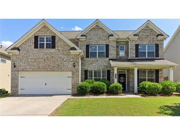 Charming brick two-story home featuring a manicured lawn, two car garage, and welcoming front porch at 7130 Ansley Park Way, Cumming, GA 30028
