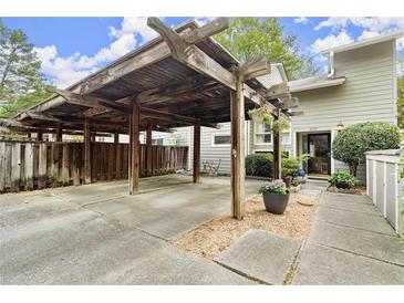 Attached carport featuring a wooden pergola cover and walkway to the cozy townhome's front door at 2060 Clairmeade Ne Way, Atlanta, GA 30329