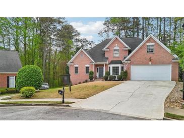 Charming two-story red brick home featuring a manicured lawn, two-car garage, and beautiful bay window at 740 Trillium Ln, Lilburn, GA 30047