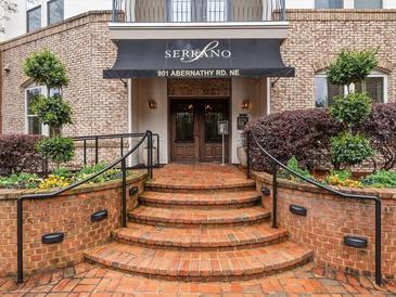 Inviting building entrance with brick steps, manicured landscaping and a black awning with white lettering at 901 Abernathy Ne Rd # 3200, Atlanta, GA 30328