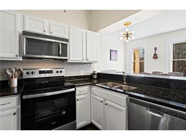 Well-lit kitchen featuring stainless steel appliances, dark countertops, and white cabinets at 2855 Peachtree Ne Rd # 115, Atlanta, GA 30305