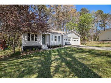 Charming single-story home featuring an attached two-car garage, a well-manicured lawn, and mature trees at 90 Chimney Rise Ct, Stockbridge, GA 30281