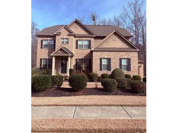 Traditional brick home featuring manicured landscaping, a gabled roof, and a welcoming front entrance at 227 Shellbark Dr, Mcdonough, GA 30252