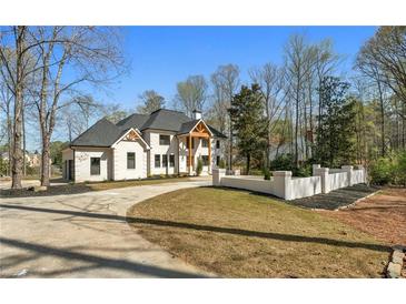 Stately two-story home with a circular driveway, lush landscaping, and a classic white brick facade at 450 Birkdale Dr, Fayetteville, GA 30215