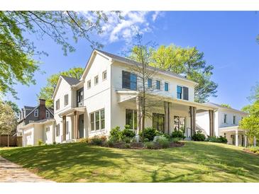 Beautiful two-story home featuring a lush green lawn, white painted brick, and a welcoming front porch at 48 25Th St, Atlanta, GA 30309