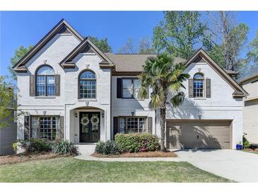 Charming two-story brick home with a well-manicured lawn and a beautiful palm tree at 6770 Ulster Ct, Alpharetta, GA 30005