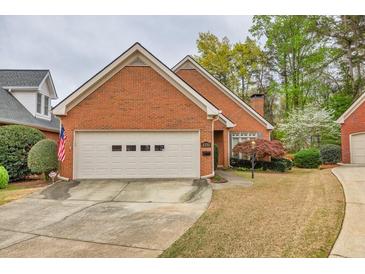 Charming brick home features a two-car garage, manicured lawn and mature trees at 2330 Burlington Ln, Snellville, GA 30078