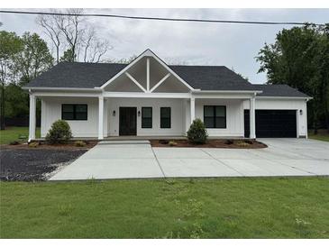 Charming one-story home with a black roof, white siding and a large driveway at 4824 Highway 20 Se, Conyers, GA 30013