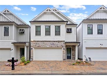 Charming two-story home with brick driveway, stone accents, white siding, and a two-car garage at 756 Stickley Oak Way, Woodstock, GA 30189