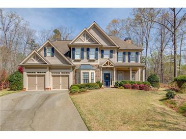Charming two-story home featuring a manicured lawn, three-car garage, and inviting blue front door at 5808 Deer Crossing Dr, Sugar Hill, GA 30518
