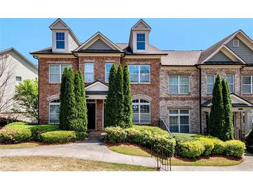Charming brick townhome featuring dormer windows and manicured landscaping, creating a welcoming curb appeal at 7620 Stoneridge Dr, Atlanta, GA 30328