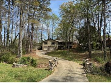 Charming home nestled in wooded area featuring a long driveway and mature trees at 302 Chattahoochee Way, Woodstock, GA 30188