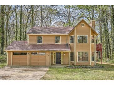 Charming two-story home features a three-car garage and lovely front yard surrounded by mature trees at 714 Post Road Dr, Stone Mountain, GA 30088