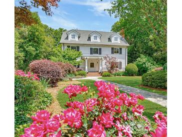 Charming two-story home with lush landscaping, including vibrant roses and mature trees at 235 The Prado N, Atlanta, GA 30309